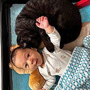 Gabriele is registered to the contest to win money with this photo: baby, cat, cuddling, blanket, toy, onesie, mat, playpen, curious, cute, furry, resting, comfort, indoor, child, pet, sleeping_cat, colorful, necklace, soft