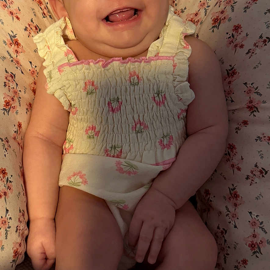 Ariyah Kassing is registered to the contest to win money with this photo: baby, bow, child, closeup, cushion, cute, expression, floral_outfit, happy, headwear, indoor, infant, patterned_cushion, person, pink_bow, portrait, sitting, skin, smiling, young_child