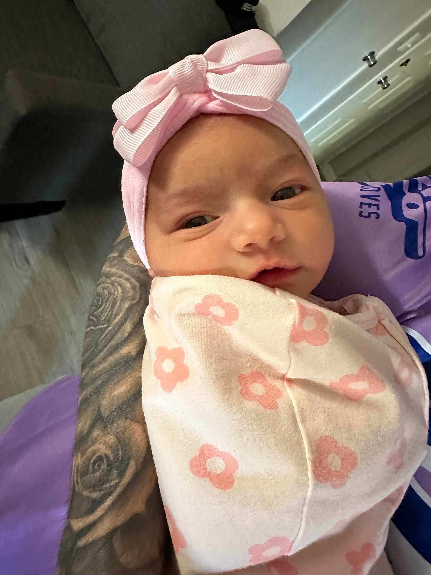 Ariyah Kassing is registered to the contest to win money with this photo: baby, infant, pink_bow, blanket, tattoo, arm, indoor, person, face, headband, sleepy, curious, floral_pattern, closeup, newborn, soft_lighting, cuddle, human, wrapped, portrait