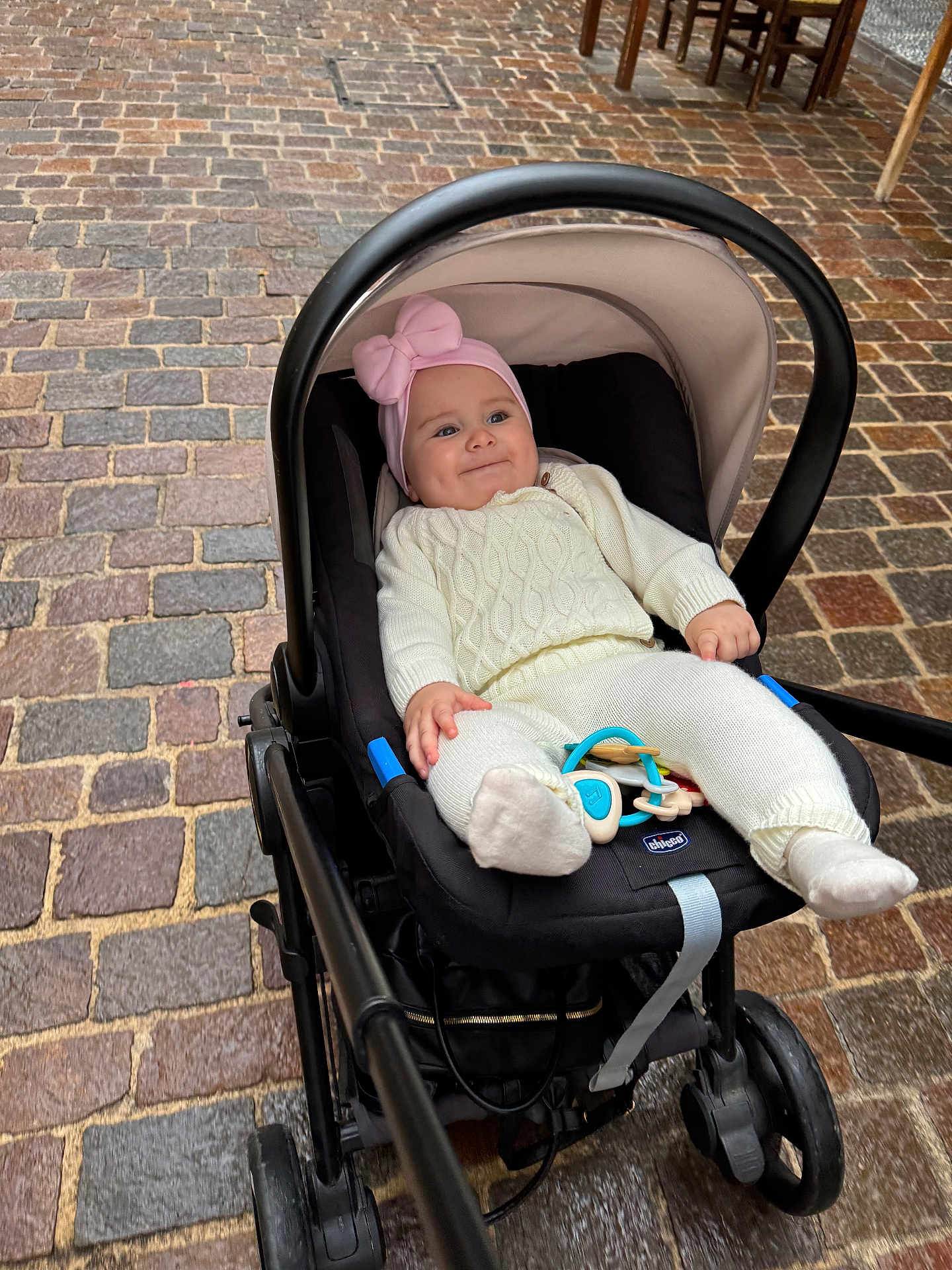 Miia a rejoint le concours — aidez-le/la à gagner de superbes lots ! baby, stroller, infant, pink_hat, white_clothing, cobblestone, outdoor, smile, child, seat, toy, footwear, person, cute, knitwear, headwear, expression, wheels, hand, cozy