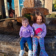 Braelon joined the competition — help win amazing prizes! children, kids, smiling, fountain, rock, water, brick, outdoor, daylight, clothing, hoodie, pants, shoes, building, plants, happy, two_people, sitting, casual, young