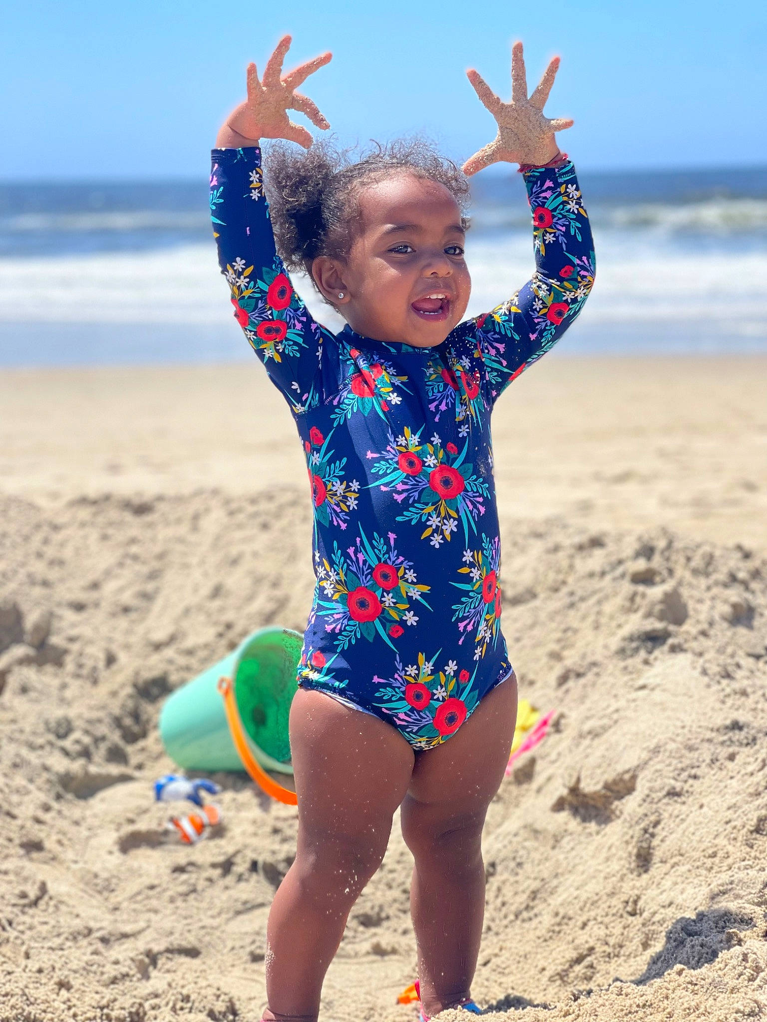 Jordyn is registered to the contest to win money with this photo: azure, barefoot, beach, electric_blue, fun, gesture, happy, leisure, neck, people_in_nature, people_on_beach, person, sky, sleeve, smile, summer, t_shirt, thigh, toddler, travel