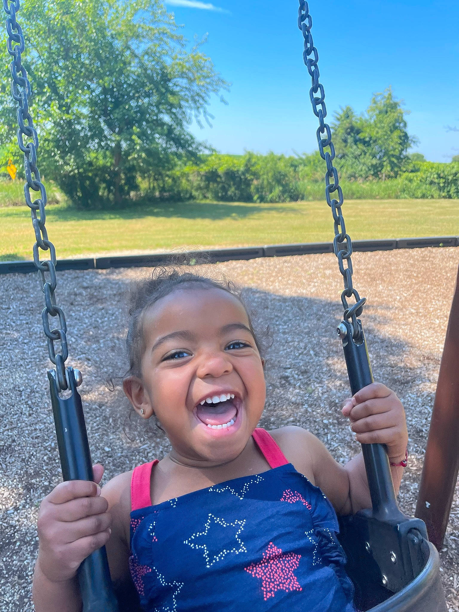 Jordyn is registered to the contest to win money with this photo: arm, black, blue, eye, facial_expression, green, hand, happy, head, human, human_body, natural_environment, person, photograph, plant, sky, smile, standing, swing, tree