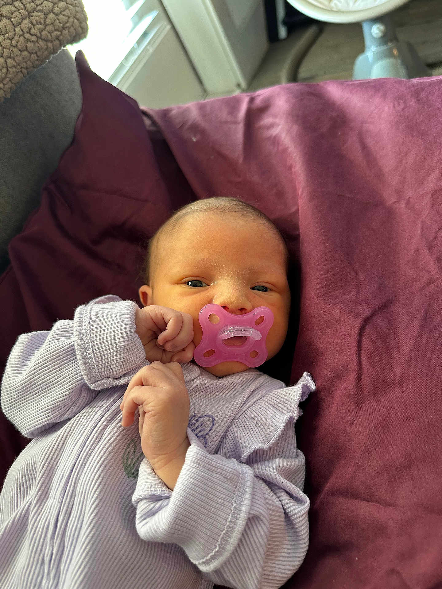 Reeslynn is registered to the contest to win money with this photo: baby, newborn, infant, pacifier, pink_pacifier, onesie, purple_blanket, pillow, bed, face, eyes, tiny_hands, cozy, indoor, soft_texture, portrait, cute, relaxing, sleepy, blanket