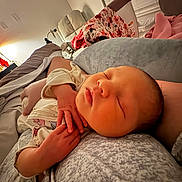 Reeslynn is registered to the contest to win money with this photo: baby, newborn, sleeping, infant, bed, pillow, blanket, hand, bedding, soft_light, indoors, cozy, portrait, close_up, lamplight, nightstand, patterned_blanket, clothing, resting, nursery