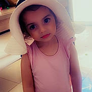 Layana participe au concours pour gagner de l'argent avec cette photo : child, girl, hat, pink_clothing, shorts, indoor, floor, expression, face, person, standing, curious, large_eyes, sunhat, casual, young, portrait, home, soft_lighting, toy