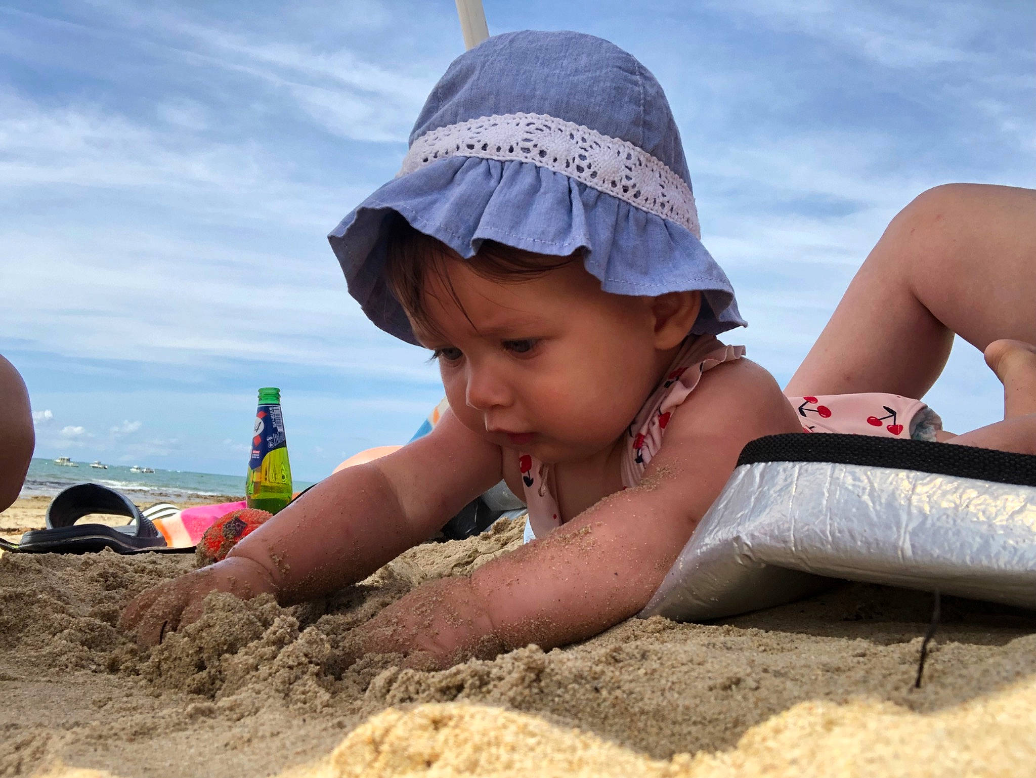 Leïna participe au concours pour gagner de l'argent avec cette photo : barefoot, beach, cap, child, cloud, fun, happy, hat, headwear, landscape, leisure, people_in_nature, people_on_beach, person, recreation, sand, sitting, sky, soil, sun_hat