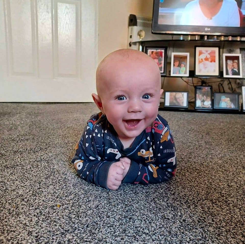 Samuel Scott is registered to the contest to win money with this photo: baby, baby_toddler_clothing, cable_television, carpet, child, comfort, crawling, floor, flooring, fun, home_appliance, led_backlit_lcd_display, person, picture_frame, road_surface, sleeve, smile, television, television_set, toddler