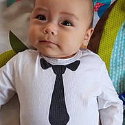 Loic participe au concours pour gagner de l'argent avec cette photo : baby, infant, child, face, eyes, clothing, onesie, tie_print, bowtie_print, hand, blanket, pattern, colorful, lying_down, portrait, cute, soft_light, indoors, person, young_child