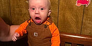 Maverick joined the competition — help win amazing prizes! baby, child, infant, overalls, orange_shirt, crib, mattress, hand, wood_paneling, wall_decoration, cartoon_stickers, face, standing, expression, indoor, person, furniture, clothing, toy, room