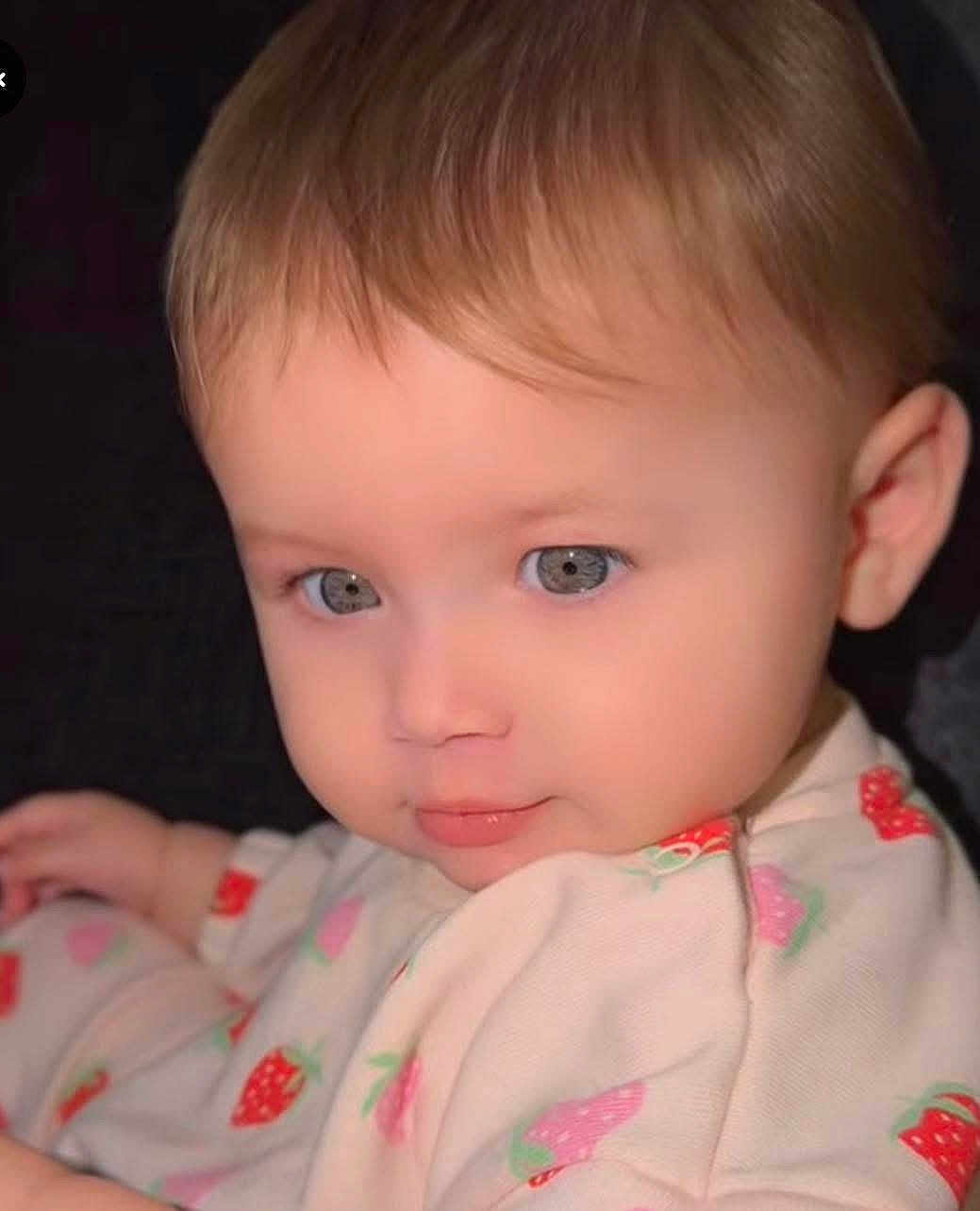 Aysha joined the competition — help win amazing prizes! baby, child, face, blue_eyes, brown_hair, strawberry_print, clothing, infant, portrait, cute, soft_lighting, close_up, young_child, sitting, looking_away, skin, eyebrows, ear, expression, baby_girl