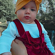 Aysha joined the competition — help win amazing prizes! baby, child, face, head_wrap, yellow, red_dress, velvet, outdoor, trees, sky, hand, person, cute, infant, portrait, clothing, holding, expression, nature, young