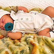 Jayce joined the competition — help win amazing prizes! baby, infant, sleeping, pacifier, white_outfit, hat, socks, blanket, bed, portrait, close_up, indoors, lying_down, peaceful, cozy, soft_texture, patterned_blanket, newborn, resting, photography