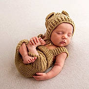 Ronnie is registered to the contest to win money with this photo: baby, newborn, sleeping, knitted_clothing, hat, bear_ears, infant, cute, peaceful, soft_texture, blanket, portrait, small_hands, small_feet, resting, cozy, child, one_person, indoor, closeup