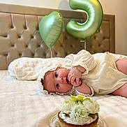 Vanessa participe au concours pour gagner de l'argent avec cette photo : baby, balloon, bed, blanket, blue_eyes, bonnet, bracelet, cake, celebration, cupcake, flower_topping, flowers, headboard, heart_balloon, infant, number_5_balloon, party, portrait, tufted_headboard, white_dress