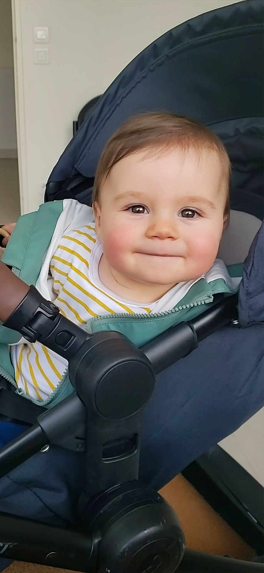 Eden a rejoint le concours — aidez-le/la à gagner de superbes lots ! baby, child, closeup, clothing, cute, face, handlebar, happy, head, indoor, jacket, person, rosy_cheeks, seated, smile, striped_shirt, stroller, transport, wheel, young_child