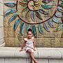 accessories, architecture, building, child, clothing, dress, face, female, footwear, girl, head, path, pattern, person, photography, portrait, sandal, shorts, sitting, wall