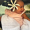 baby, child, flower, blanket, pink_clothing, smile, face, portrait, indoor, car_interior, cute, happy, young_child, head, skin, person, seat, window, natural_light, cozy