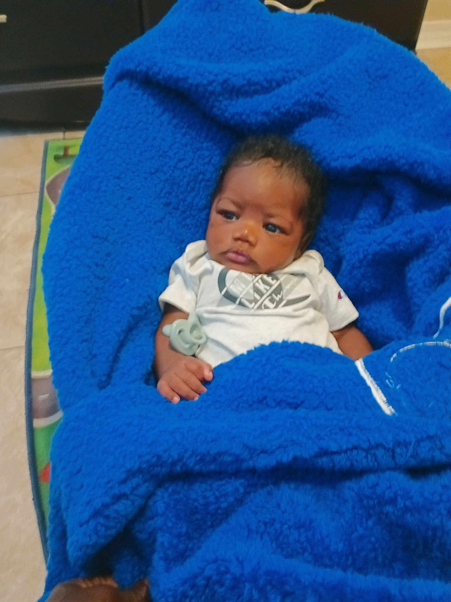 Bryan is registered to the contest to win money with this photo: baby, blanket, blue_blanket, infant, pacifier, clothing, person, face, hand, indoors, floor, expression, portrait, resting, toddler, cute, warm, soft, cozy, child