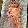 baby, infant, headband, bow, romper, clothing, patterned_blanket, tongue_out, lying_down, cute, smiling, hand, foot, skin, person, indoors, wood_floor, texture, fabric, happy