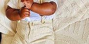 Oneal is registered to the contest to win money with this photo: baby, infant, smiling, lying_down, clothing, shorts, shirt, suspenders, socks, cute, happy, face, skin, hands, legs, textile, blanket, pattern, indoors, portrait