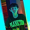 David is registered to the contest to win money with this photo: child, boy, smiling, tshirt, plankton, glowing_lights, blue_light, indoor, colorful, musical_notes, background, short_hair, standing, casual_clothing, youth, happy, portrait, person, fun, lighting