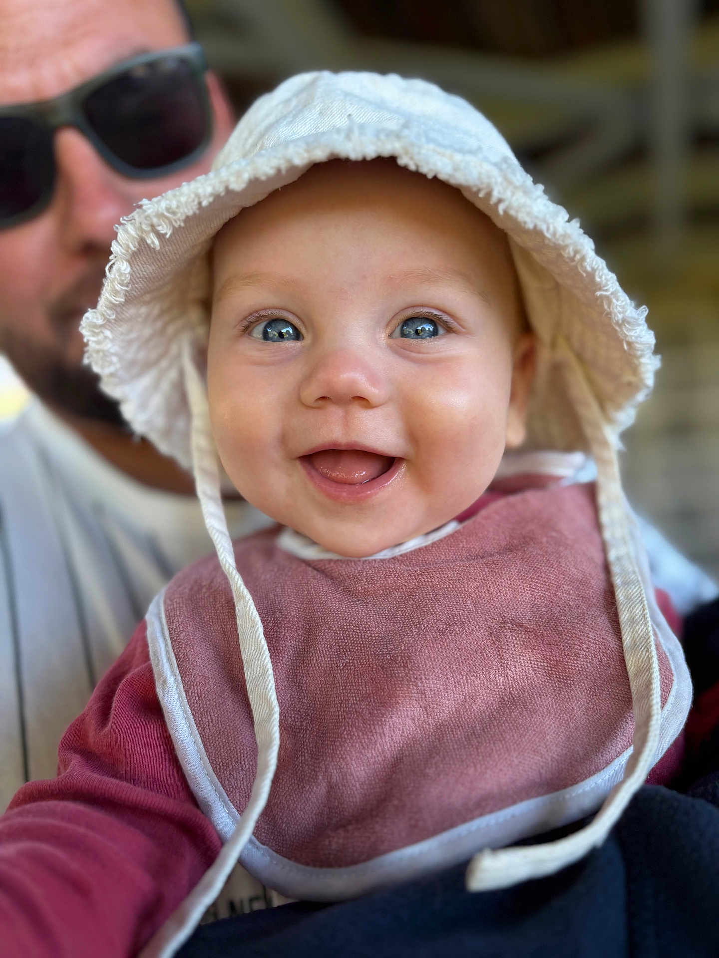 Charlie participe au concours pour gagner de l'argent avec cette photo : baby, smiling, face, hat, bib, child, person, closeup, happy, blue_eyes, adult, sunglasses, background_blur, casual_clothing, portrait, indoor, cute, infant, headwear, joyful