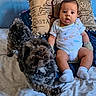 baby, infant, dog, pet, bed, pillow, blue_wall, clothing, onesie, mittens, socks, animal_print, fur, cute, playful, person, indoor, expression, furniture, portrait