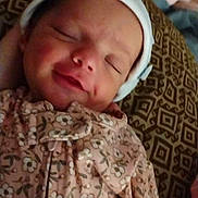 Hazel is registered to the contest to win money with this photo: baby, blanket, child, cozy, cute, floral_clothing, human, indoor, infant, newborn, onesie, patterned_cushion, peaceful, portrait, resting, sleeping, smile, soft_lighting, white_cap, young_child