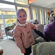 Charlie a rejoint le concours — aidez-le/la à gagner de superbes lots ! carpet, casual_clothing, child, couch, curtains, furniture, girl, happy, heart_pattern, home, indoor, living_room, modern, natural_light, person, pillow, pink_sweater, smiling, stroller, window