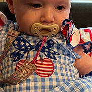 Everleigh joined the competition — help win amazing prizes! baby, pacifier, blue_checkered_outfit, headwear, bow, cherry_design, ruffled_sleeves, red_white_blue, sitting, infant, face, clothing, cute, indoor, portrait, child, small_child, person, closeup, soft_lighting