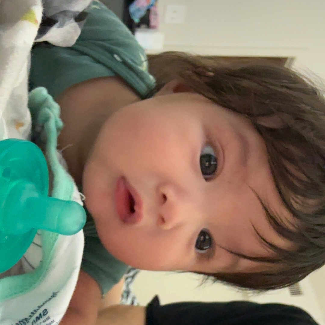 Isaiah is registered to the contest to win money with this photo: baby, infant, pacifier, blanket, face, curious, wide_eyes, tousled_hair, person, indoor, clothing, home, child, young, lying_down, textile, soft, comfort, casual, portrait