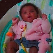 Harmony is registered to the contest to win money with this photo: baby, infant, pink_jacket, denim_shorts, baby_seat, cushion, toy, curly_hair, raised_arms, indoor, blanket, comfort, child, portrait, expression, clothing, seat, baby_accessory, soft_toys, greeting_text