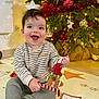 baby, child, smiling, indoor, christmas_tree, ornament, holiday, decorations, playmat, toy, festive, happy, sitting, clothing, face, person, floor, light, joy, cute