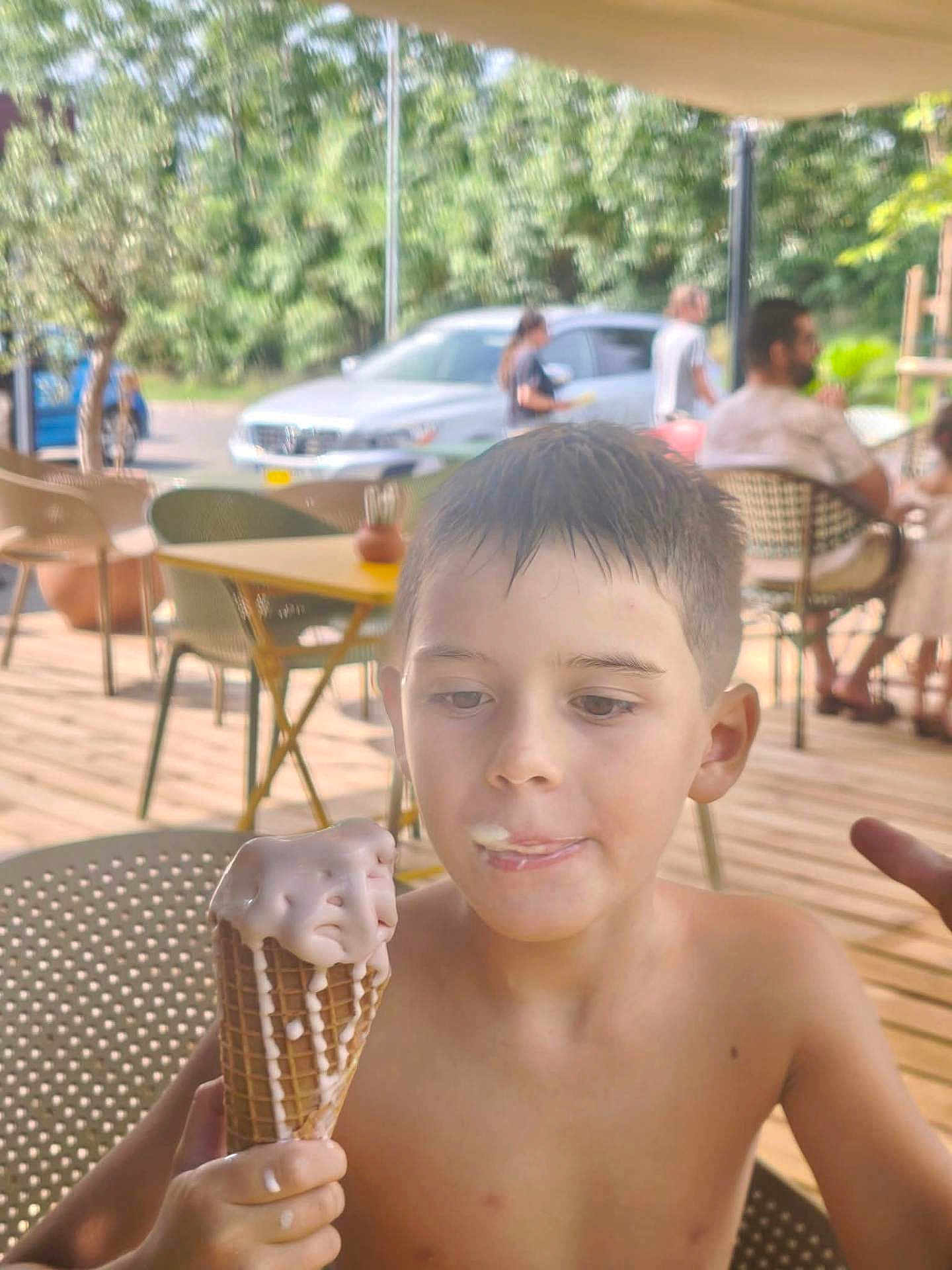 Petru Maria participe au concours pour gagner de l'argent avec cette photo : child, boy, ice_cream, cone, melting, summer, outdoor, patio, wet_hair, food, sweet, happy, casual, table, chair, people, car, daylight, nature, relaxed