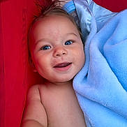 Kasen is registered to the contest to win money with this photo: baby, child, smiling, blue_eyes, blanket, red_background, happy, face, skin, arm, closeup, portrait, infant, cute, soft_texture, lying_down, baby_bottle, hair, indoors, toddler