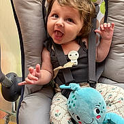 Eléana a rejoint le concours — aidez-le/la à gagner de superbes lots ! baby, child, infant, smiling, happy, curly_hair, plush_toy, octopus, seat, baby_seat, straps, clothing, patterned_pants, cute, playful, indoor, portrait, person, young_child, expression