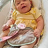 baby, baby_blanket, bouncer, chubby_cheeks, closeup, clothing, curly_hair, feet, hand, happy, headband, infant, nursery, pacifier_clip, portrait, seat_cushion, skin, smiling, soft_lovey, yellow_dress