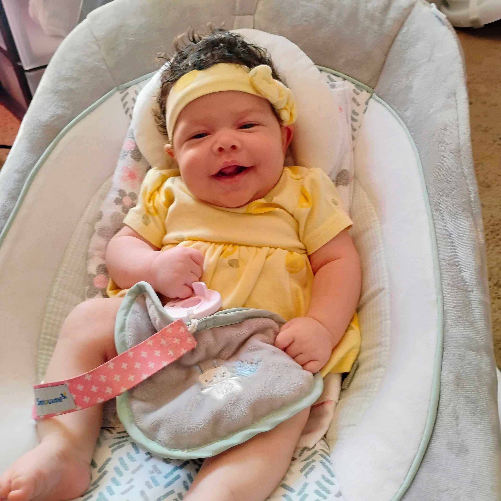 Trinity joined the competition — help win amazing prizes! baby, baby_seat, blanket, bouncer, carpet, chubby_cheeks, curly_hair, cushion, foot, hand, happy, headband, indoors, infant, lovey, pacifier, portrait, smiling, soft_toy, yellow_dress