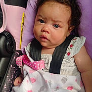 Trinity joined the competition — help win amazing prizes! baby, infant, car_seat, blanket, face, child, straps, clothing, pink, purple, cute, expression, curly_hair, comfort, seatbelt, pattern, embroidery, soft_texture, portrait, indoors
