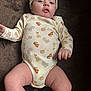 Emmett Sherwood joined the competition — help win amazing prizes! baby, infant, child, onesie, hat, animal_print, giraffe, tiger, lion, face, legs, arms, soft_surface, brown_background, cute, clothing, looking, curious, indoors, portrait
