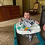 Emmett is registered to the contest to win money with this photo: baby, walker, toy, blanket, pajamas, carpet, cabinet, chair, television, living_room, foot, person, child, furniture, home, curly_hair, indoor, carpeted_floor, cloth, hand