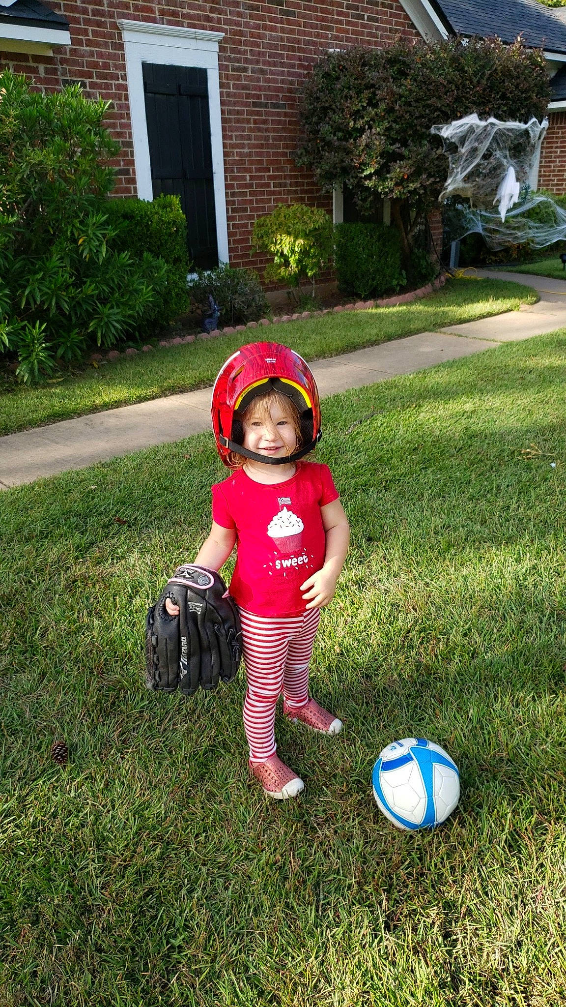 Elsa is registered to the contest to win money with this photo: baby, baby_products, baby_toddler_clothing, backyard, bag, ball, door, football, garden, headwear, lawn, luggage_and_bags, person, play, playing_sports, soccer, soccer_ball, sun_hat, toddler, toy