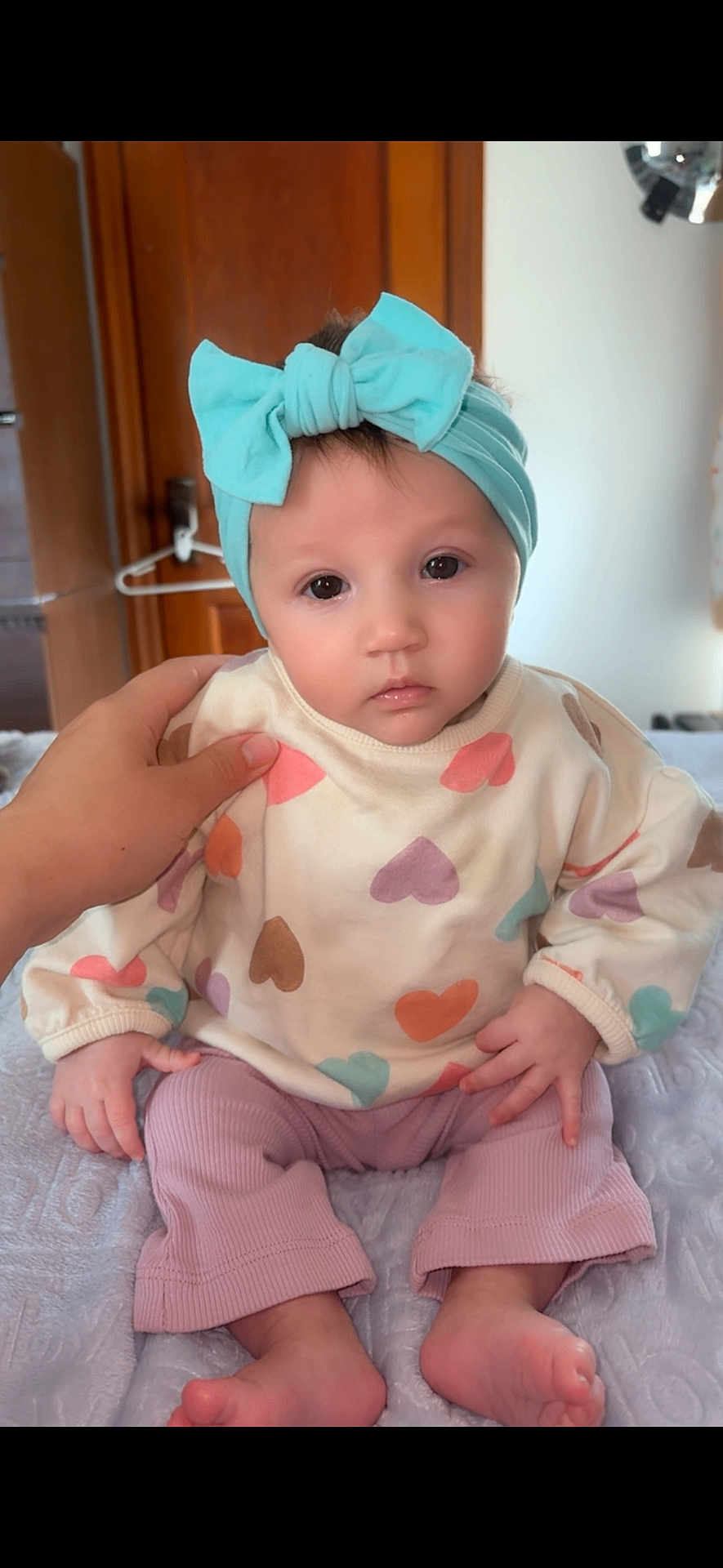 Marleyrae joined the competition — help win amazing prizes! baby, child, headband, bow, sweater, heart_pattern, pink_pants, bare_feet, hand, indoor, soft_blanket, curious_eyes, portrait, infant, cute, supporting_hand, wooden_door, calm_expression, clothing, person