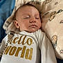 baby, infant, sleeping, onesie, glitter_text, blanket, animal_print, soft_texture, closeup, face, peaceful, cute, child, bed, cozy, newborn, skin, head, clothing, indoors