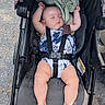 baby, stroller, sleeping, infant, child, outdoor, pavement, sunlight, clothing, blanket, resting, safety_harness, legs, feet, head, person, summer, cute, relaxing, nap