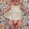 Rikku is registered to the contest to win money with this photo: baby, child, infant, dress, sunhat, patterned_clothing, blanket, woodland_animals, squirrels, rabbits, birds, floral_pattern, cute, laying_down, indoors, soft_lighting, chubby_legs, curious_expression, portrait, colorful_background