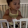 Zahmiyah Frison joined the competition — help win amazing prizes! toddler, child, crib, yellow_bow, yellow_tank_top, curly_hair, indoor, baby, person, furniture, bed, sleep_area, standing, looking_away, curious, clothing, skin, hair_accessory, expression, home
