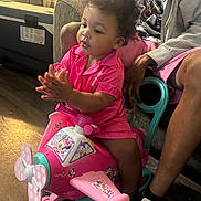 Zahmiyah Frison joined the competition — help win amazing prizes! adult, airplane, casual_clothing, child, clapping, curly_hair, family, floor, fun, furniture, happy, indoor, living_room, minnie_mouse, pink, play, ride_on_toy, sneakers, toddler, toy