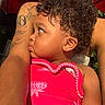 toddler, child, curly_hair, earring, pink_outfit, strawberry_pattern, tattoo, adult_arm, sunlight, close_up, profile, outdoor, umbrella, protective, embrace, skin, person, summer, warm_light, love